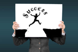 穿西裝的人手持帶有跳躍人物和 success 字樣的標牌 — 成功 壁紙