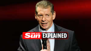 穿西裝的男子手持帶有「The U.S. Sun Explained」標誌的麥克風。 — WWE GIF 壁紙