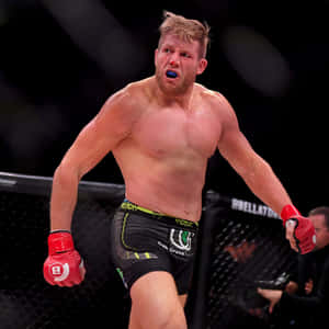 一名男性MMA戰士戴著紅色手套和藍色護齒套，在籠中慶祝勝利。 — 運動 壁紙