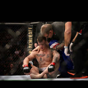 一名落敗的MMA拳手在八角籠內接受醫護人員治療。 — 運動 壁紙
