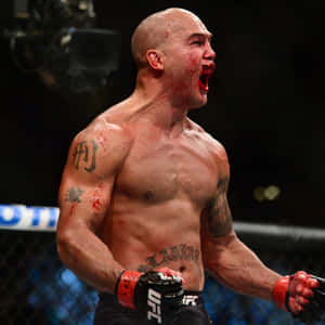 一名滿臉鮮血、帶有刺青的勝利MMA拳手在八角籠內慶祝。 — 終極格鬥冠軍賽 壁紙