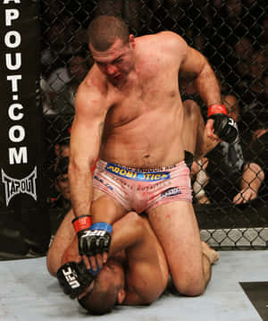 MMA拳手穿粉紅色短褲在籠式八角籠內壓制對手。 — 終極格鬥冠軍賽 壁紙