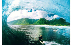 衝浪者在山巒背景下於捲曲的海浪下滑行。