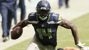 西雅圖海鷹隊美式足球員在比賽中帶球奔跑。 — Dk Metcalf 壁紙