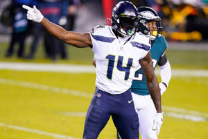 穿著海鷹隊球衣的足球員在夜間比賽中指著。 — Dk Metcalf 壁紙