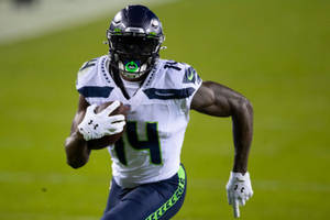 西雅圖海鷹隊美式足球員在夜間帶球奔跑。 — Dk Metcalf 壁紙