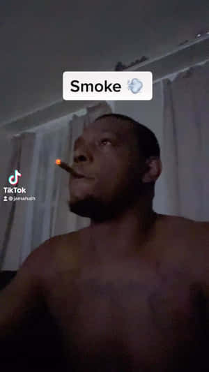 一名赤裸上身的男子在夜間於室內抽著點燃的雪茄煙。 — 抽菸 壁紙