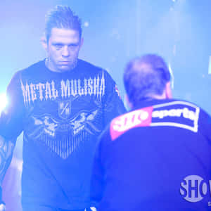 兩名戰士在藍色燈光的 MMA 競技場中對峙，身穿品牌襯衫。 — 終極格鬥冠軍賽 壁紙