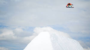 滑雪板運動員在半空中飛越積雪坡道，陰天 — 雪山 壁紙