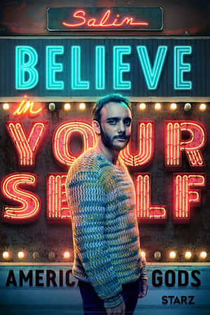 身穿針織毛衣的男子站在發光的「Believe in Yourself」霓虹燈牌前，為American Gods宣傳。 — 聖經中的天使 壁紙