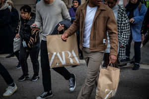 男子手持Zara購物袋，穿過擁擠的城市街道。 — Zara 壁紙