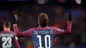 足球運動員內馬爾（Neymar Jr）在夜間球場高舉雙臂慶祝。 — 巴黎聖日耳曼 壁紙