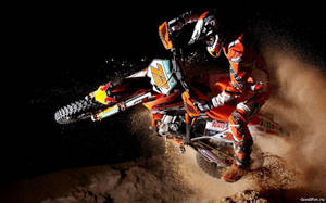 越野摩托車手在夜間駕駛越野摩托車轉彎，揚起灰塵。 — X Games 壁紙