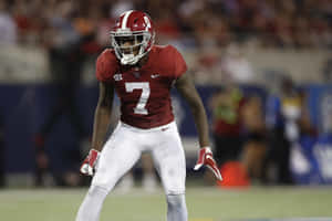 身穿紅色七號球衣的足球員在夜間場地上蹲著。 — Stefon Diggs 壁紙