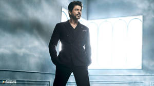 身穿深色西裝的男子自信地站在有明亮窗戶的霧氣房間中。 — 阿盧·阿瓊 壁紙