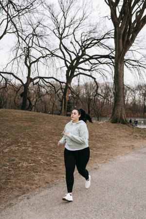 女子在冬季被無葉樹木環繞的公園小徑上慢跑。 — Running 壁紙