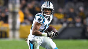 美式足球員在球場燈光下帶球奔跑。 — NFL 美式足球 壁紙