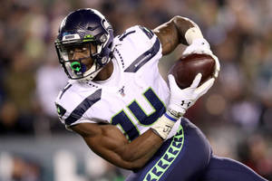 西雅圖海鷹隊美式足球員在夜間比賽中接住美式足球。 — Dk Metcalf 壁紙