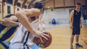 運動員在室內比賽中運球，防守球員在附近。 — 運動 壁紙