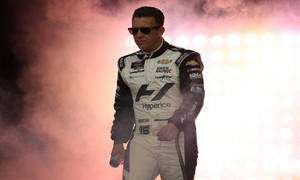 NASCAR車手身穿賽車服在夜間明亮的燈光下穿過煙霧。 — 運動 壁紙