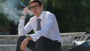 戴眼鏡的年輕男子在戶外混凝土台階上抽煙。 — 抽菸 壁紙