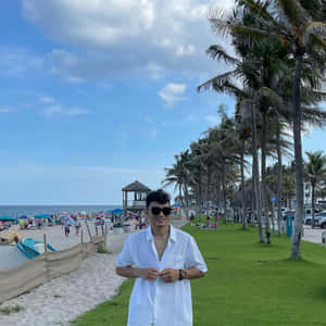 身穿白襯衫和太陽眼鏡的男子在擠滿棕櫚樹的海灘上微笑。 — 海灘 壁紙