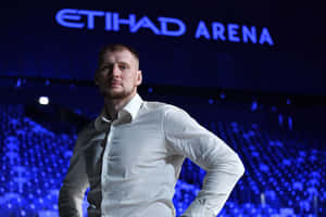 白襯衫男子在Etihad Arena藍色燈光下自信擺姿勢。 — 運動風 壁紙