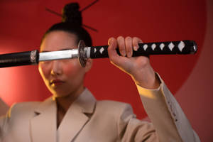 身穿米色西裝的人將武士刀橫在臉前，背景紅色 — 混沌武士 壁紙