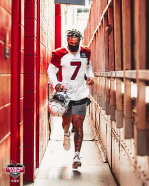 身穿 Cardinals 球衣的足球員手持頭盔跑過紅磚隧道。 — 席尼·墨菲 壁紙