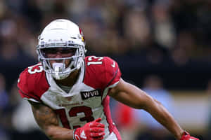 身穿 Cardinals 球衣的美式足球員在夜間比賽中奔跑。 — 運動 壁紙