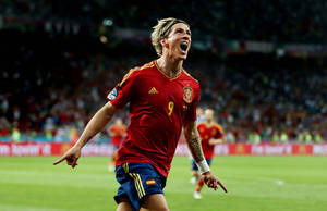 身穿紅色球衣的足球員在燈光球場上慶祝勝利。 — 費爾南多·托雷斯 壁紙