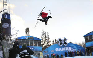 滑雪者在X Games雪地活動中表演後空翻，觀眾和品牌帳篷。 — X Games 壁紙