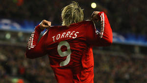 足球運動員 Torres 在夜間將紅色 9 號球衣拉過頭頂慶祝。 — 費爾南多·托雷斯 壁紙