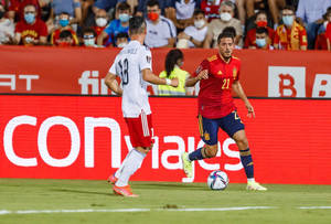 身穿紅色球衣的足球員在比賽中運球，對手身穿白色球衣。 — FIFA 世界盃 壁紙
