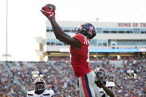 足球員在日間比賽中接住傳球，背景有群眾。 — Dk Metcalf 壁紙