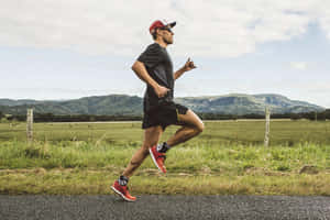 男子在鄉村道路上慢跑，背景有山丘 — Running 壁紙