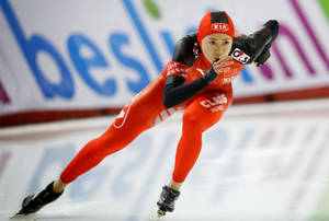身穿紅色套裝的女子速度滑冰選手在溜冰場上比賽 — 運動 壁紙