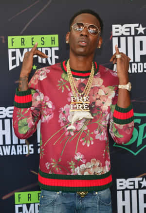 身穿花卉毛衣和金色鏈條的男子在BET嘻哈頒獎典禮上擺姿勢。 — Young Dolph 壁紙
