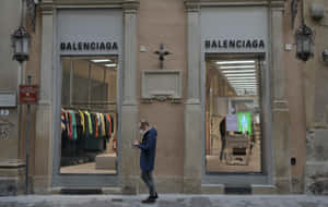 戴口罩的男子在城市街道上走過 Balenciaga 時裝店。 — 巴黎世家 壁紙