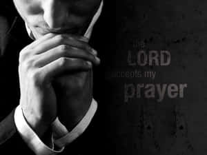 西裝男雙手合十祈禱，深色牆上有「the LORD accepts my prayer」文字。 — 祈禱 壁紙