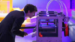 穿西裝的男子在科技展覽中觀察帶有紫色燈光的3D列印機。 — 3D 壁紙
