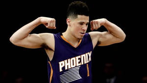 籃球運動員在比賽中穿著鳳凰城太陽隊球衣彎曲手臂。 — Devin Booker 壁紙