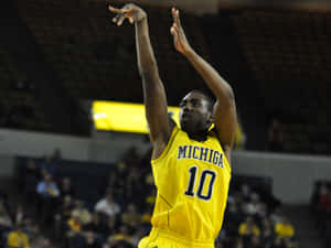 籃球運動員身穿黃色密西根球衣投籃。 — 運動 壁紙