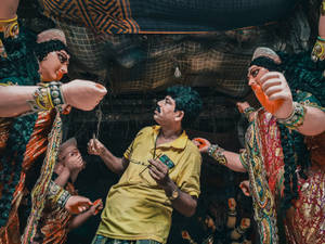 男子在節日期間被大型雕像頑皮地噴灑彩色粉末。 — Maa Durga 壁紙