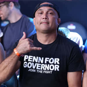 身穿「Penn for Governor」襯衫的男子在活動中做出沙卡手勢。 — 運動 壁紙