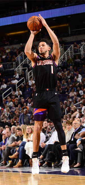 籃球運動員在歡呼的人群前跳投。 — Devin Booker 壁紙