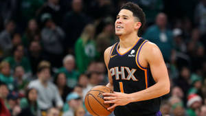 鳳凰城太陽隊籃球運動員在比賽中持球，背景有觀眾。 — Devin Booker 壁紙