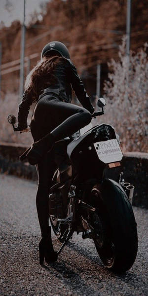 身穿黑色皮革的女性在日落時分騎摩托車在碎石路上 — 酷女孩 壁紙
