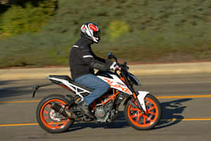 摩托車騎士在陽光明媚的道路上騎乘KTM Duke，背景有動態模糊效果。 — 男人 壁紙