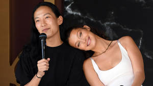 兩名女子，一人手持麥克風在室內大理石牆附近微笑 — 貝拉·哈蒂德 壁紙